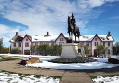 Historic Fort Calgary wooden buildings alongside river on a cloudy day