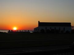 Silhouette of chapel against an orange sunset sky