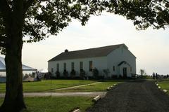 Small chapel next to a gravel driveway surrounded by trees