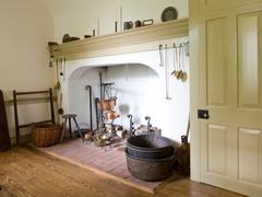 Open hearth kitchen with pots and cooking utensils around large fireplace