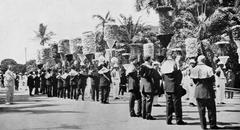 Funeral procession marchers wearing feather ahuulas and holding sacred kahilis at the Royal Mausoleum