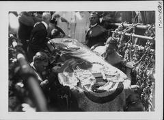 Funeral procession of Jonah Kūhiō Kalanianaʻole with people gathered around traditional hearse in 1922