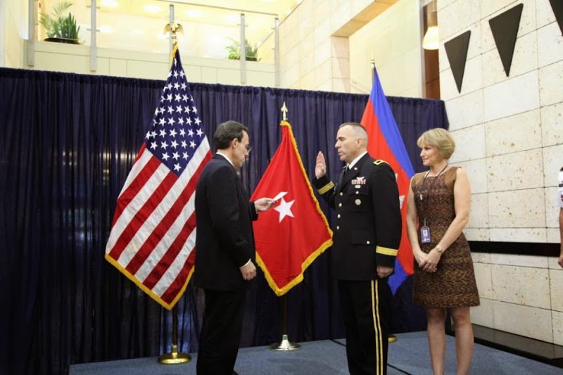 Ambassador William Todd administering oath of Brigadier General to Mark Gillette accompanied by his wife Ingrid