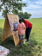 Camp staff helping child with painting during summer camp at Hampton National Historic Site