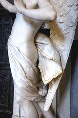 Detailed view of a cemetery sculpture featuring a gold-trimmed angel garment