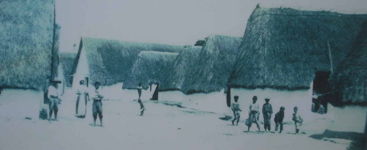 Early 20th century view of El Palmar village with traditional buildings and mountain backdrop