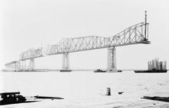 Black and white photograph of cantilever construction of Huey P. Long Bridge over Mississippi River in 1935