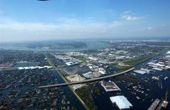 Aerial view of flooded neighborhoods and highways near the Orleans/Jefferson Parish line in New Orleans after Hurricane Katrina, showing the Hollygrove and Carrollton neighborhoods, Water treatment plant, Parish Line levee, Earhart Expressway, Oschener Medical Center, and Huey P. Long Bridge.
