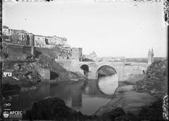 Fortified Alcántara Bridge over Tagus River with Toledo city in the background