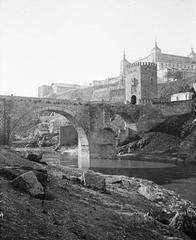 Fortified Alcántara Bridge over Tagus River with city of Toledo in background