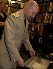 Admiral James Stavridis examining a naval manual at Pritzker Military Library during NATO photo exhibition in Chicago