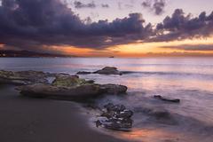 Sunset view at Playa de la Misericordia beach with palm trees and cloudy sky in Spain