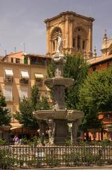 Fountain of Neptune at Plaza Bib-Rambla with cathedral tower in background in Granada Spain