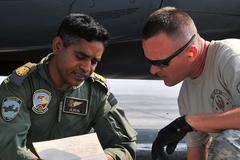 Nepalese Army and US Air Force personnel collaborating with Bangladesh and Indian Air Force members to offload relief supplies from a C-130 Hercules in Kathmandu