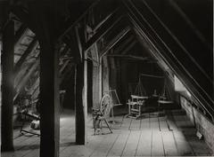 Interior view of the second attic of Saint-Gabriel farm showing two spinning wheels, a book stand, a churn, and a scale