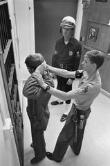 Corporal Thomas preparing to handcuff an unauthorized absentee serviceman while Master-At-Arms 1st Class Getman watches on shore patrol duty