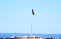 Tall flagpole with Azerbaijani flag in Baku city under clear blue sky