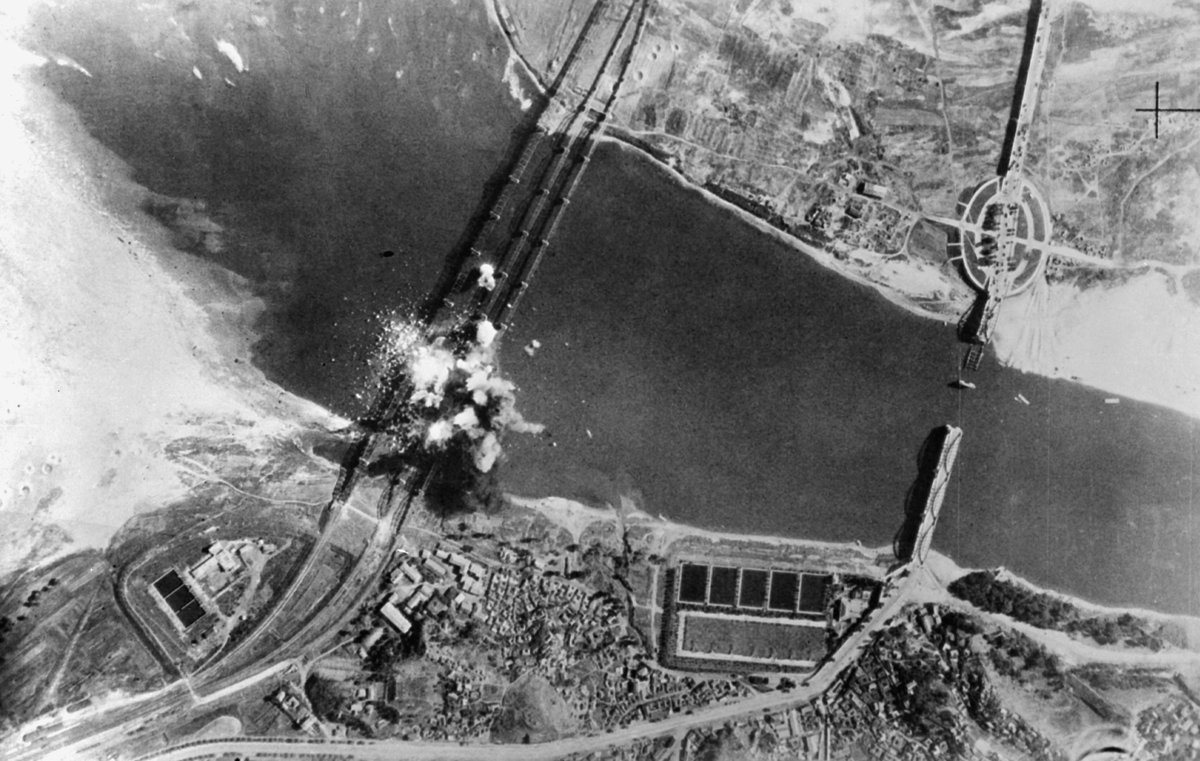 Aerial view of U.S. Air Force bombs exploding on three parallel railroad bridges over Han River near Seoul during Korean War