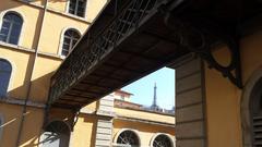 View of the metal tower of Fourvière in Lyon from behind the Subsistances buildings with a wooden and metal footbridge in the foreground