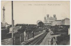 Black and white postcard view of Tramway Fourvière at Loyasse with the metallic tower and Basilica of Fourvière in the background, taken from the tramway viaduct now known as Passerelle des Quatre-Vents