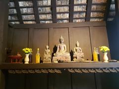 Buddhist images and offerings displayed on a shelf at Siam Society Headquarters in Bangkok, Thailand