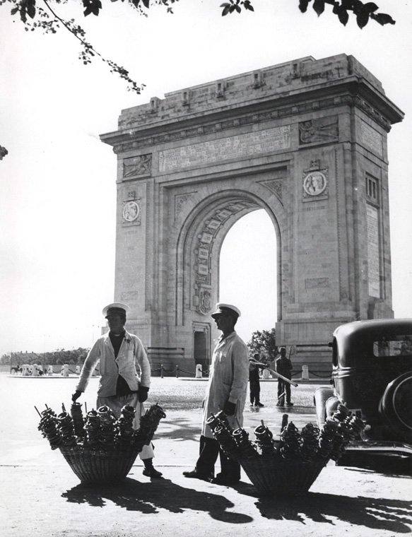 Pretzel vendors in uniform standing in front of the Triumph Arch
