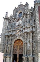 Main portal of La Santisima Church in Mexico City with intricate architectural details and large wooden doors