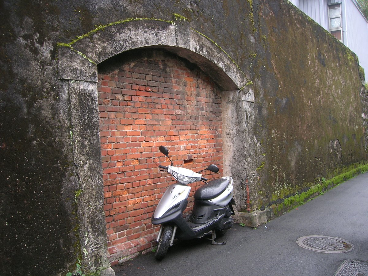Remains of Taipei Prison Gate with a Yamaha Jog scooter parked nearby