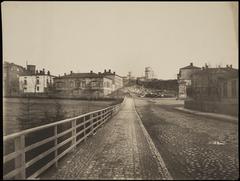 Historical black and white view of Vuorimiehenkatu buildings 7, 9, 11 and Tähtitorninkatu 10 behind, located at present-day Ullanpuistikko in Helsinki with water post and the observatory of Helsinki University atop Tähtitorninvuori hill