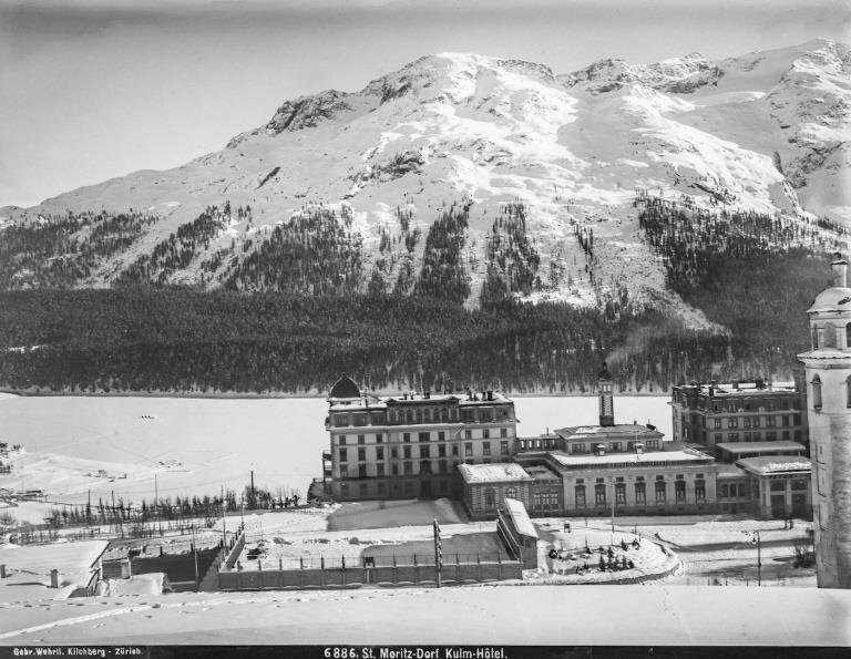 St. Moritz hotel Kulm with frozen lake and forested mountain slope in the background