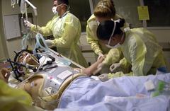 Navy Hospital Corpsmen and Medical Officers assessing treatment of a gunshot wound patient in ICU