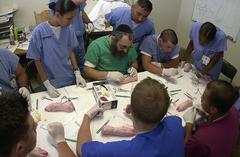 Arnold Zigman in green scrubs teaching Navy Hospital Corpsmen and Medical Officers wound stitching at USC Medical Center in Los Angeles