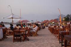 Seafood restaurants with bamboo huts on Jimbaran Beach at sunset in Bali, Indonesia