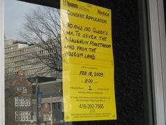 Yellow paper sign on window door of The McLaughlin Planetarium saying 'to sell the land'