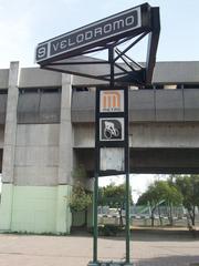 Velódromo Station sign with trees and blue sky background