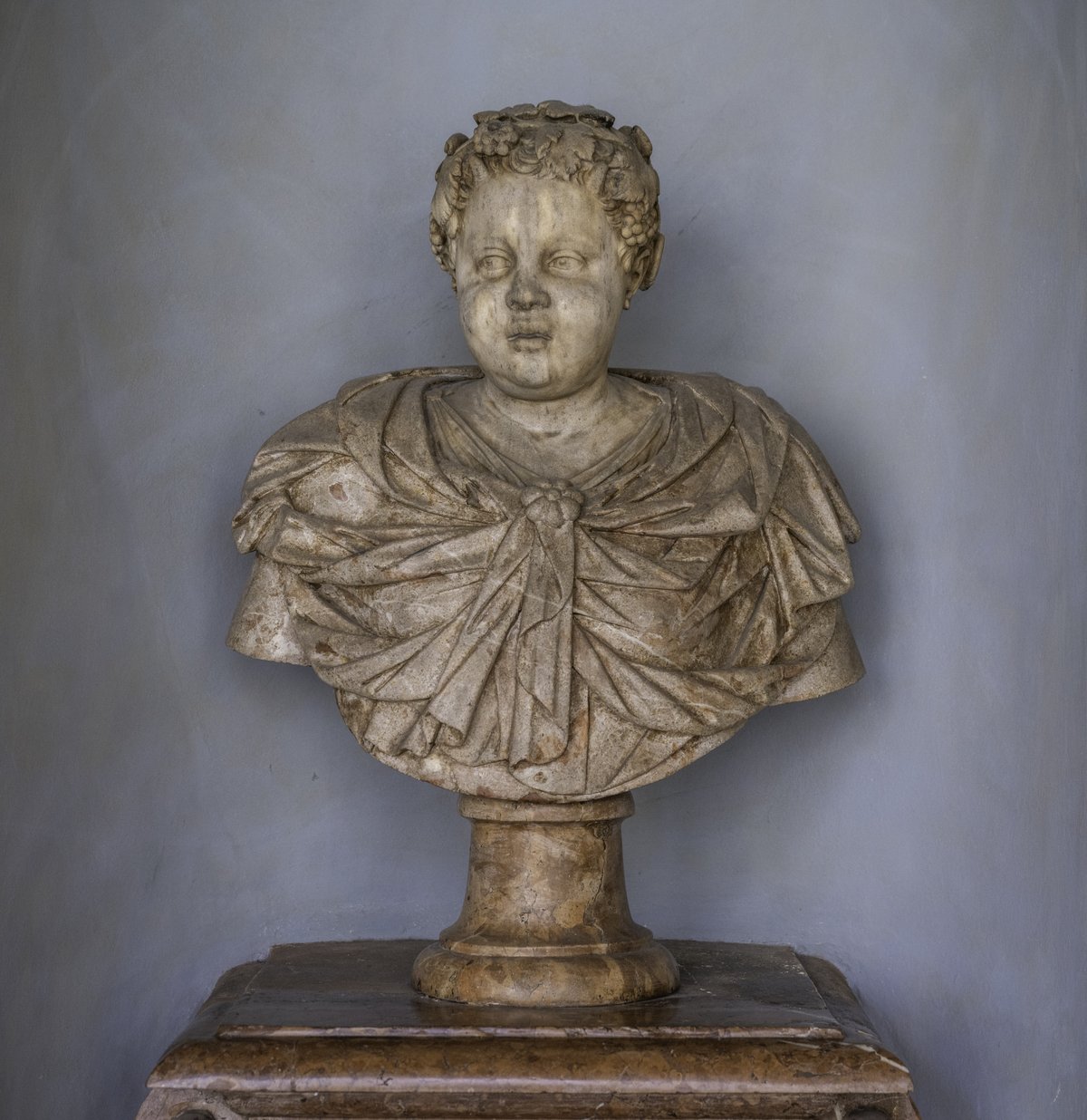 Marble bust of a child wearing a draped cloak and vine-leaf wreath in Munich Residenz