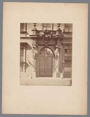 Historical photograph of the side portal entrance of Stadtpalais Liechtenstein in Vienna featuring a gate with an entrance coat of arms sculpture.