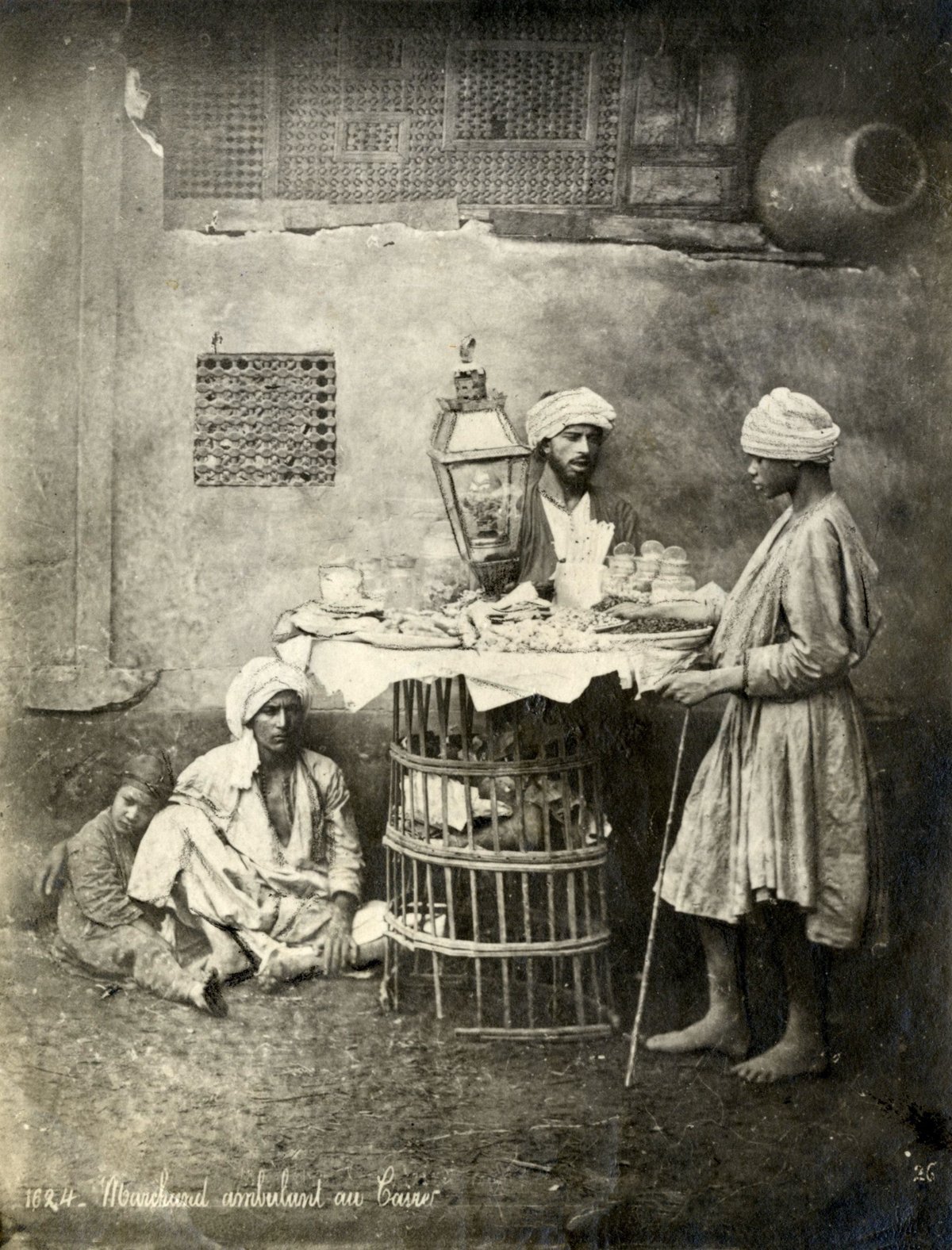 Men with turbans in Café Riche at the fish market in Cairo, Egypt 1914, with a petroleum lamp illuminating a wicker sales table