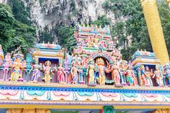 Entrance to Batu Caves with large golden statue and limestone hills