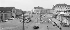 View of the station square in Karlsruhe, Germany showing cars, trams, trucks, and buildings in 1955