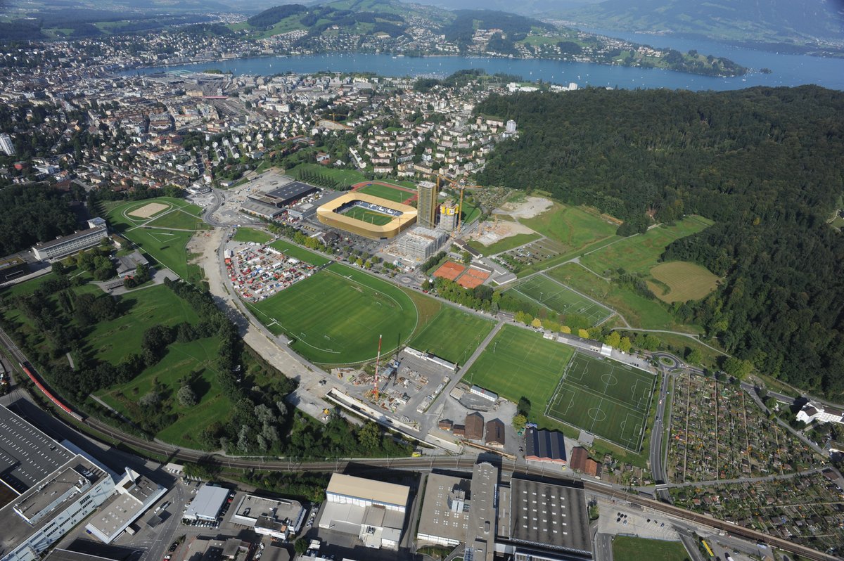 Aerial view of Lucerne Allmend showing Swissporarena stadium with the new railway tunnel route under construction curving across green area and new Lucerne Allmend/Messe railway station to the left of the stadium