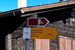 Hiker walking on a forest trail with a yellow waymark sign in the Canton of Wallis, Switzerland