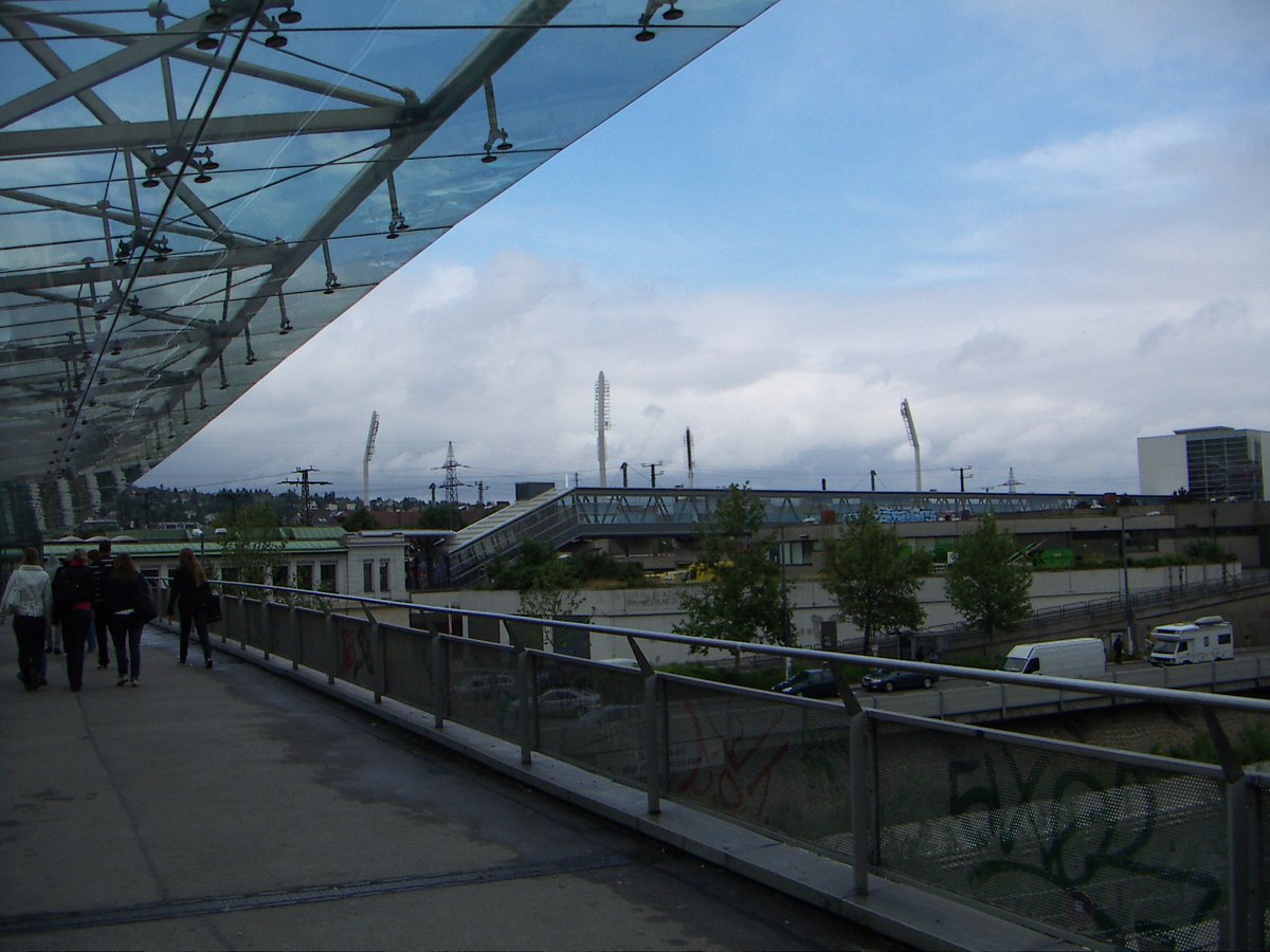 Hackinger-Steg pedestrian bridge over Wien River in Hacking, Vienna with lighting masts of Gerhard-Hanappi-Stadion in background