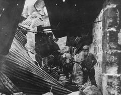 U.S. infantrymen conducting house to house search in walled city ruins during WWII