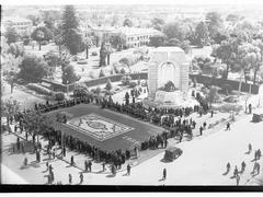 Crowd inspecting floral carpet and flowers on War Memorial at Kintore Avenue and North Terrace during Flower Day 1936