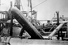 Loading an 18 inch torpedo into an early submarine with a rectangular hatch at Cavite Navy Yard Philippines circa 1912