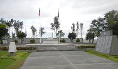 Camp Pangatian Memorial Shrine with flagpoles and memorial markers under a clear sky