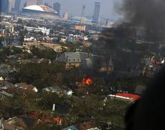 Fire burning in New Orleans neighborhood along Carrollton Avenue after Hurricane Katrina with Central Business District and damaged Superdome in background