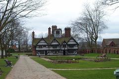 Traditional English oak timber-framed house with thatched roof and windows with flower boxes