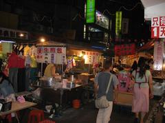 Night scene of Raohe Street Night Market in Taipei City with brightly lit stalls and busy crowd